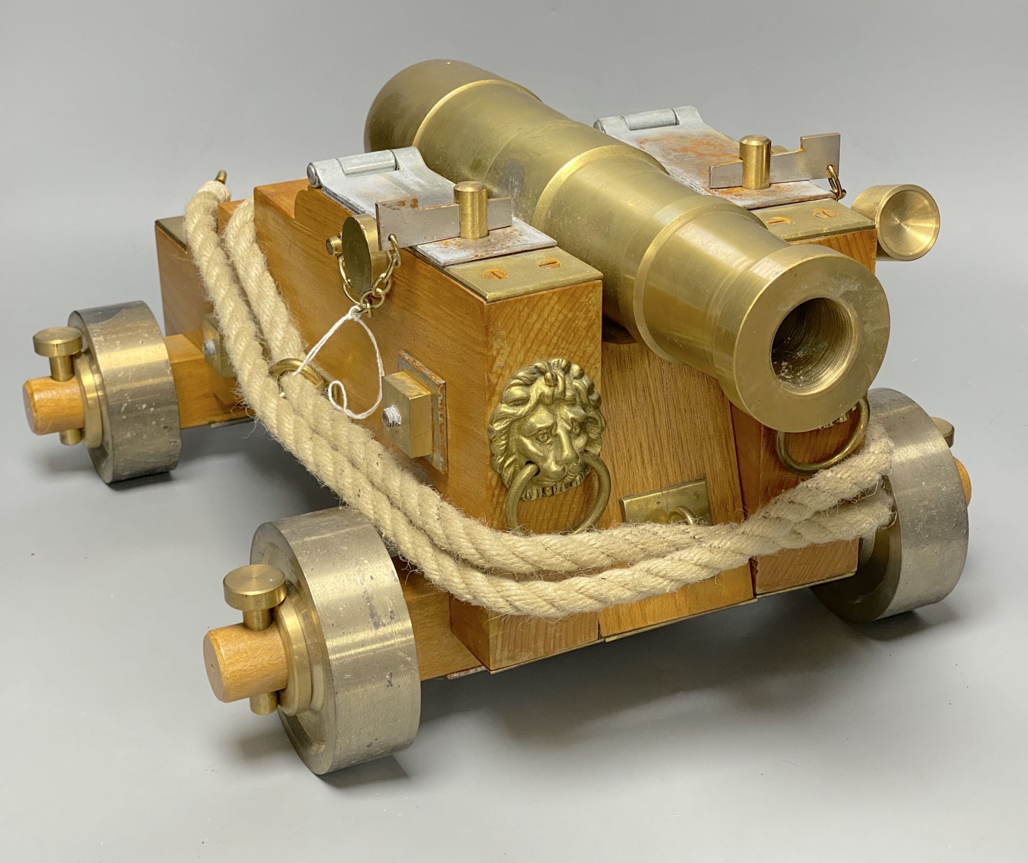 A bronze model of a cannon, on stepped wheel base with lion head motifs, length 50cm